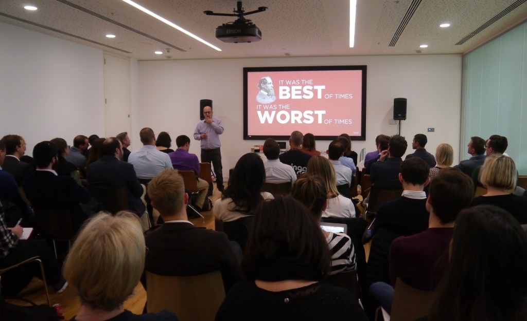 David Roth, CEO of The Store, gives his introduction to the Mindshare Future of Retail Huddle. He stands at the front of a room full of people, next to a projector screen which reads 'The best of times, the worst of times', a reference to Charles Dickens.