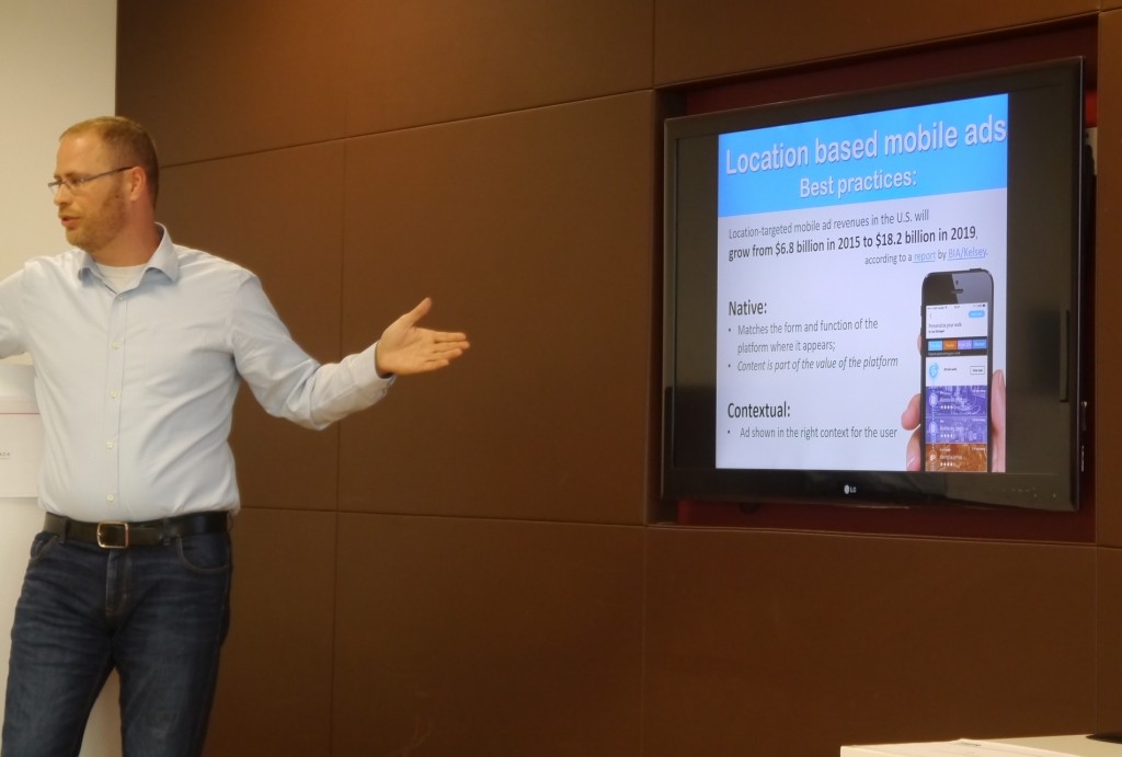 Sidekix co-founder Miron Perel gestures towards a presentation screen with some figures about location based mobile advertising.